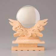 A round silver mirror resting on an intricately carved wooden stand that evokes waves or clouds.